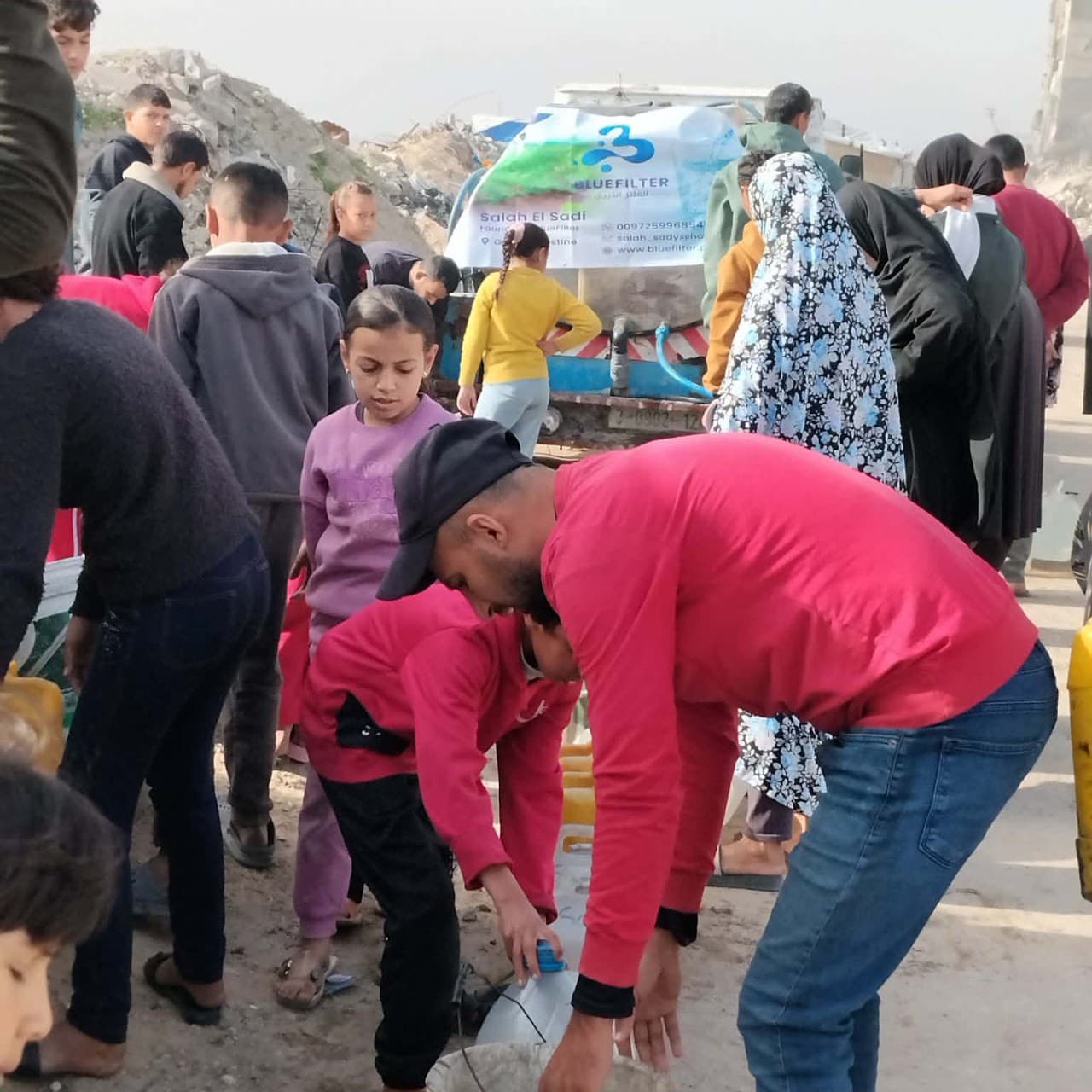 Families gathering at a Blue Filter distribution point to fill their containers