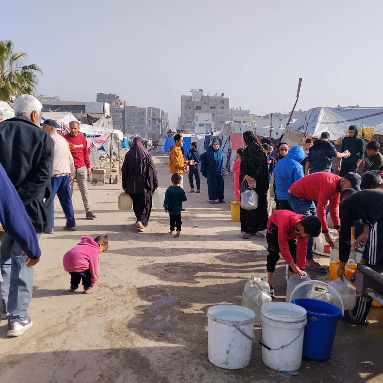 A displacement camp in Gaza where residents queue with water containers